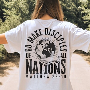 May include: White t-shirt with a black graphic design featuring a globe, hands, and the text "Go Make Disciples of All Nations Matthew 28:19".
