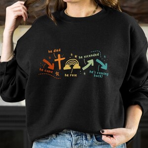 May include: Black sweatshirt with a graphic design of a cross and a rainbow. The text on the graphic reads "he died", "he came", "he rose", "he ascended", "he's coming back!"
