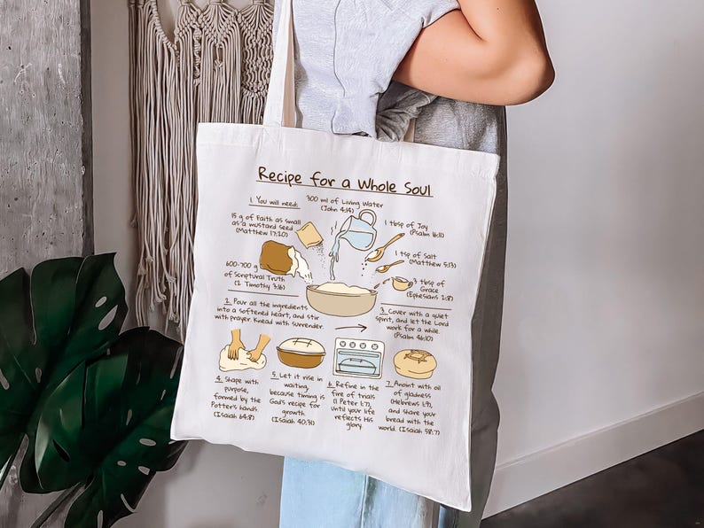 May include: White tote bag with a recipe illustration titled "Recipe for a Whole Soul." The recipe includes ingredients like living water, faith, and grace. The bag is held by a person.