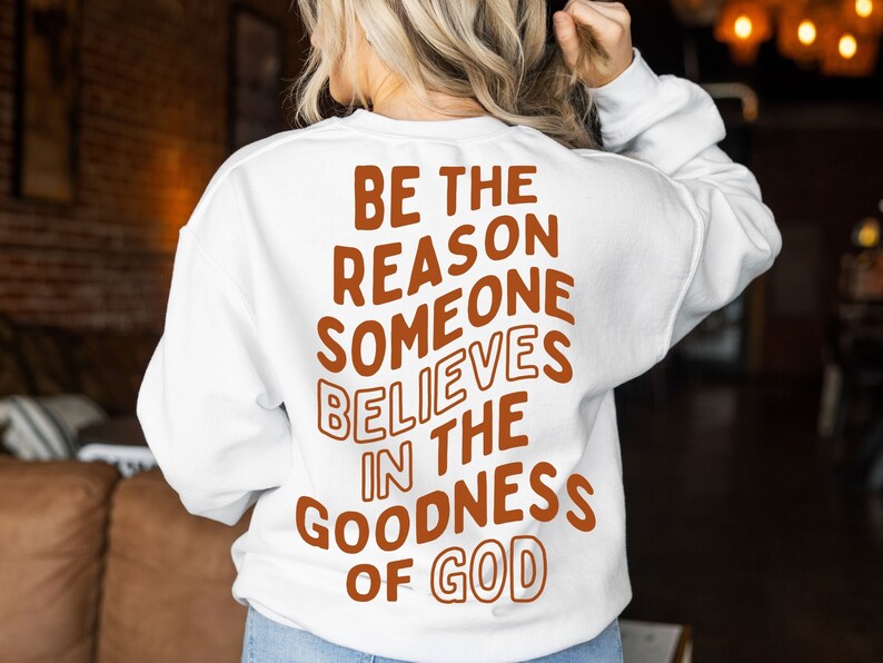 Może przedstawiać: Biała bluza z napisem "BE THE REASON SOMEONE BELIEVES IN THE GOODNESS OF GOD" w brązowych literach.