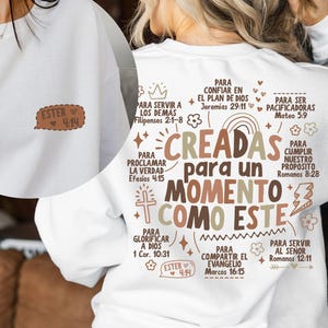 May include: White sweatshirt with the text "CREADAS para un MOMENTO COMO ESTE" in brown and beige. The back of the sweatshirt has additional text in Spanish, including "ESTER 4:14". A small patch with "ESTER 4:14" is on the front.