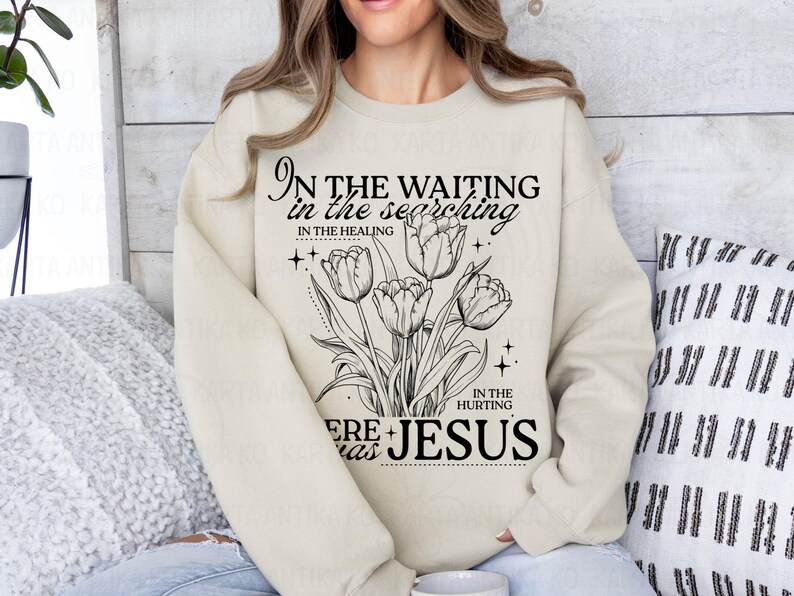 May include: Cream-colored sweatshirt featuring a black floral design with tulips and the text "In the waiting, in the searching, in the healing, in the hurting, here was Jesus." The design includes stars and decorative elements.