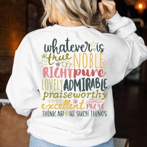 May include: White sweatshirt with colorful text on the back. The text includes words like "true," "noble," "lovely," and "admirable," along with the phrase "Think About Such Things." The design features floral and star accents.