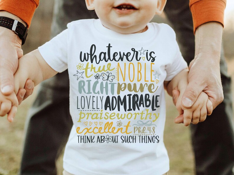 May include: White short-sleeved t-shirt with the text "whatever is true, noble, right, pure, lovely, admirable, praiseworthy, excellent" in various colors. The shirt also includes the text "Phil 4:8" and "Think about such things".
