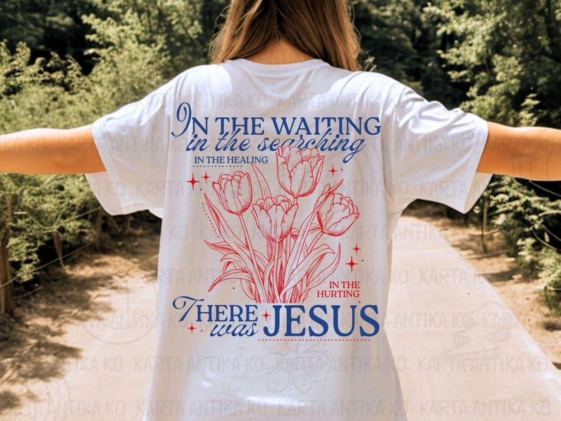May include: White t-shirt with a floral design of red tulips and the text "In the waiting, in the searching, in the healing, in the hurting, there was Jesus" in blue. The shirt has a relaxed fit.