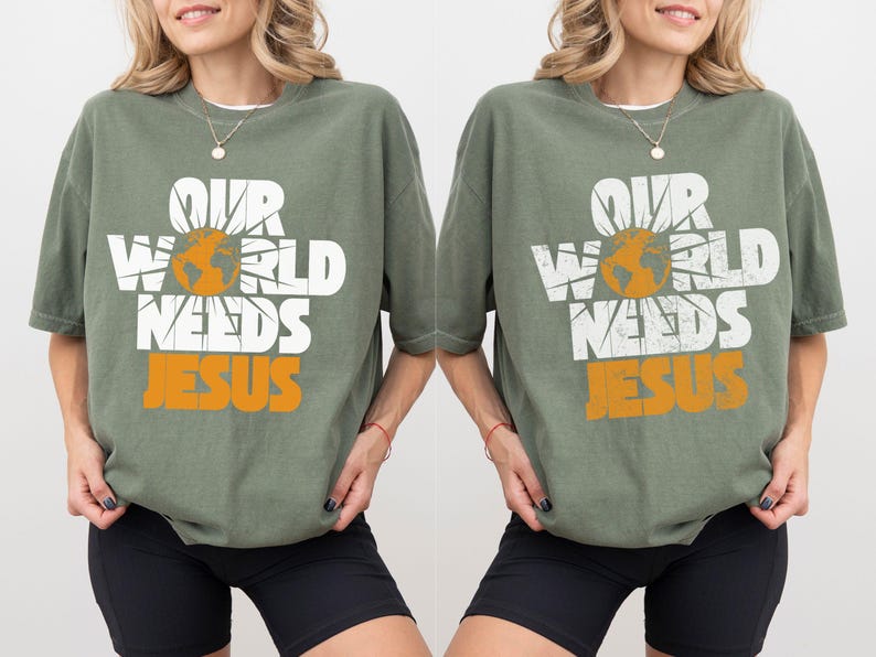 May include: Sage green t-shirt with the text "OUR WORLD NEEDS JESUS" in white and orange. The design includes a globe and sun graphic. The shirt has short sleeves and a relaxed fit.