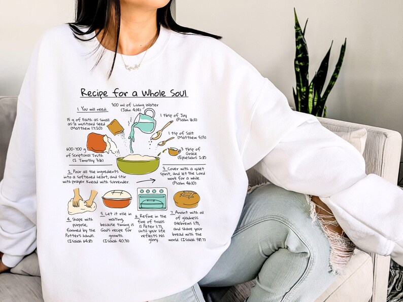 May include: White sweatshirt with a recipe graphic titled "Recipe for a Whole Soul." The graphic includes illustrated steps and ingredients like living water, mustard seed, and joy. The sweatshirt is a comfortable, casual style.