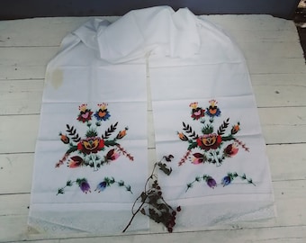 Puede incluir: Dos toallas de té de lino blanco con diseños florales bordados en tonos de rojo, naranja, amarillo, verde, azul y morado. Las toallas tienen un borde de encaje.