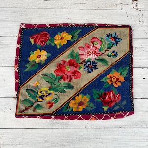 Könnte beinhalten: Ein farbenfrohes, mit Blumen besticktes Kissen mit blauem und beigefarbenem Hintergrund. Das Kissen hat einen roten, weißen und blauen Rand.