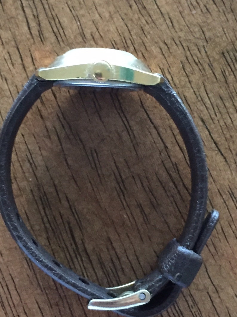 Pu&ograve; includere: Un orologio da polso argentato con un cinturino in pelle marrone e una fibbia argentata.