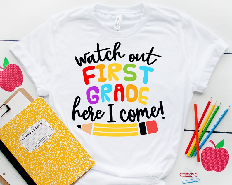 May include: White t-shirt with the text "Watch out First Grade here I come!" in rainbow colors. A yellow pencil with a red eraser is drawn below the text.