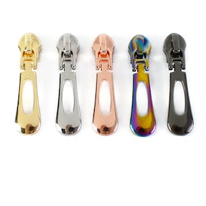 May include: Five zipper pulls in different colours: gold, silver, rose gold, iridescent, and black.