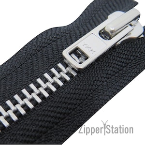 May include: Close-up of a silver zipper with a black tape. The zipper pull is silver and has a small metal tab. The tape has a textured surface.
