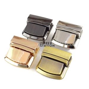 May include: Four metal clasps in different finishes: black, silver, gold, and antique brass. Each clasp is rectangular with a raised, textured surface.