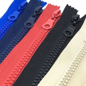 May include: Five zipper tapes in different colours: blue, red, black, beige, and white. The zippers have a plastic slider and teeth.