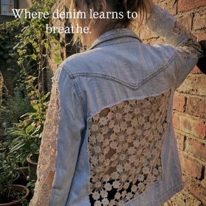 Puede incluir: Chaqueta vaquera azul claro con detalles de encaje floral en las mangas y la espalda. El texto "Where denim learns to breathe" es visible. La chaqueta es una mezcla única de diseño casual y delicado.