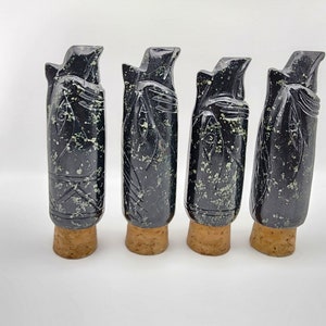 Pode incluir: Quatro rolhas de garrafa de pedra esculpida em preto e verde com bases de cortiça.