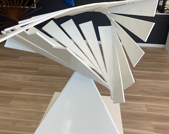 May include: White abstract sculpture made of metal, with a spiral design. The sculpture is on a white pedestal.