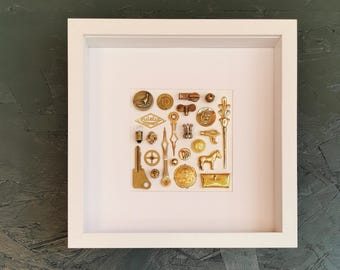 White framed display case with an assemblage of found objects "Golden Variation"