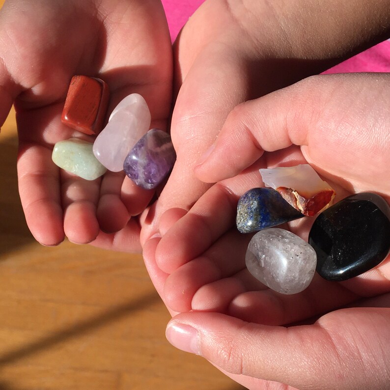 May include: A collection of seven tumbled stones in various colors, including amethyst, rose quartz, clear quartz, red jasper, green aventurine, lapis lazuli, and black obsidian.