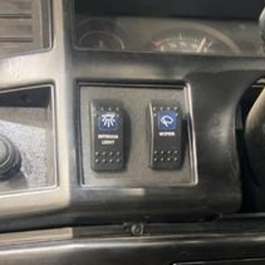 May include: Close-up of a black dashboard with two toggle switches. The switches are labeled "Intermittent Lights" and "Wipers".