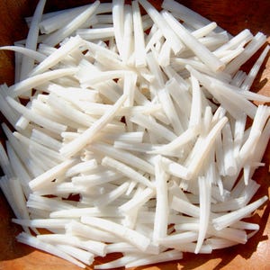 May include: A collection of numerous small, white, hollow, tapered, and cylindrical objects with a smooth texture. Each piece features a pointed end and a wider, open base, arranged in a dense, overlapping pile with a uniform off-white color.