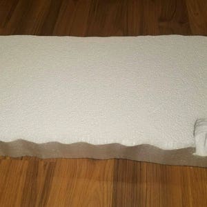 May include: White foam board with a wavy edge. The board is textured and has a slightly rough surface.