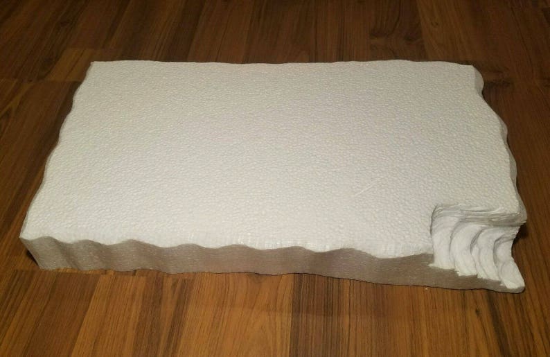 May include: White foam board with a wavy edge. The board is textured and has a slightly rough surface.