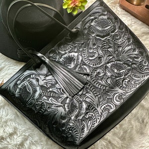 Black Handmade tooled leather tote bag for women with floral embossing, large zippered compartment, and boho-chic style. This personalized leather tote purse is perfect as a floral work bag or everyday handbag.