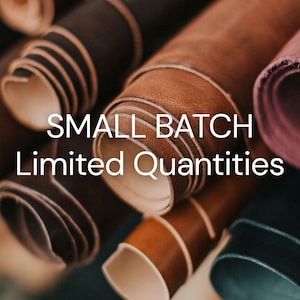 May include: Multiple rolls of leather in various shades of brown, tan, and dark tones are arranged together. The text "SMALL BATCH Limited Quantities" is overlaid in white capital and lowercase letters across the center of the leather rolls.