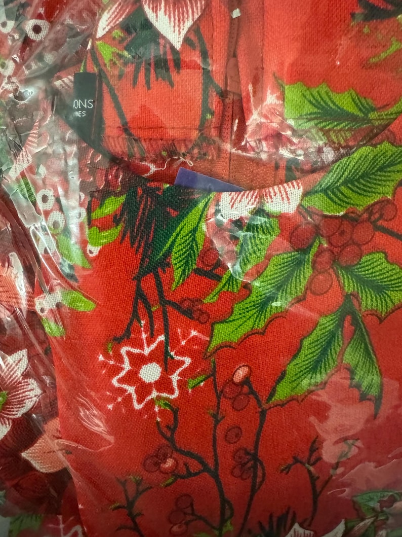 May include: Red fabric with a green and white floral pattern. The fabric has a snowflake design and the text "ONS NES" is visible in the top left corner.