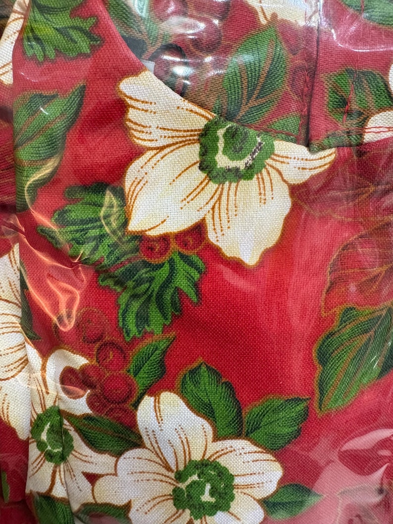 May include: Red fabric with a white floral pattern. The flowers have a green center and are surrounded by green leaves.