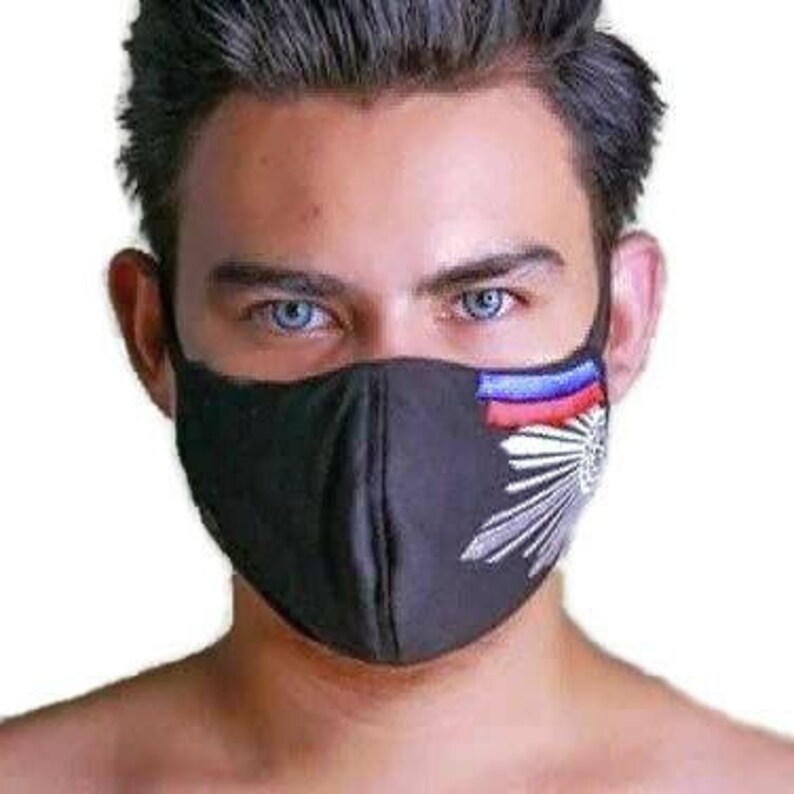 May include: Black face mask with a white and silver design featuring a stylised sunburst and a blue, white and red stripe across the top.