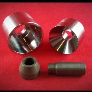 May include: Four metal tools for making jewelry. Two are silver and two are brown. The silver tools are cylindrical with a hole in the center. The brown tools are cone-shaped.