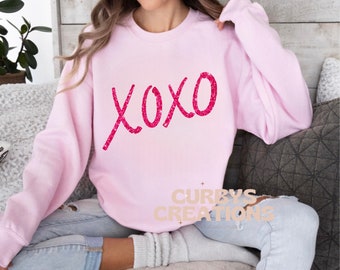May include: Pink sweatshirt with a pink glitter XOXO graphic.