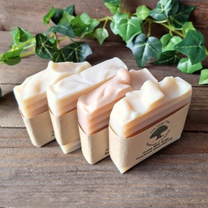 May include: Four bars of goat's milk soap wrapped in brown paper. The soap is a light beige colour and has a swirl pattern. The label on the soap reads "The Soap Tree Handmade Goat's Milk Soap with Patchouli Essential Oil".