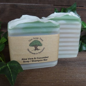May include: Two bars of green and white soap with a brown paper label that reads "The Soap Tree Handmade in Yorkshire Aloe Vera & Cucumber Soap / Shampoo Bar".
