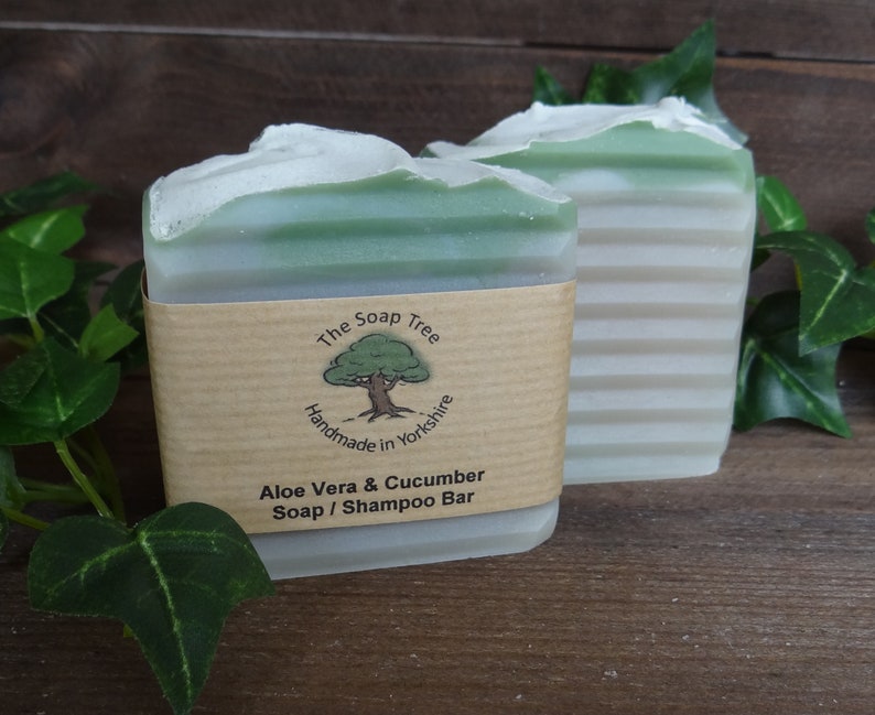 May include: Two bars of green and white soap with a brown paper label that reads "The Soap Tree Handmade in Yorkshire Aloe Vera & Cucumber Soap / Shampoo Bar".