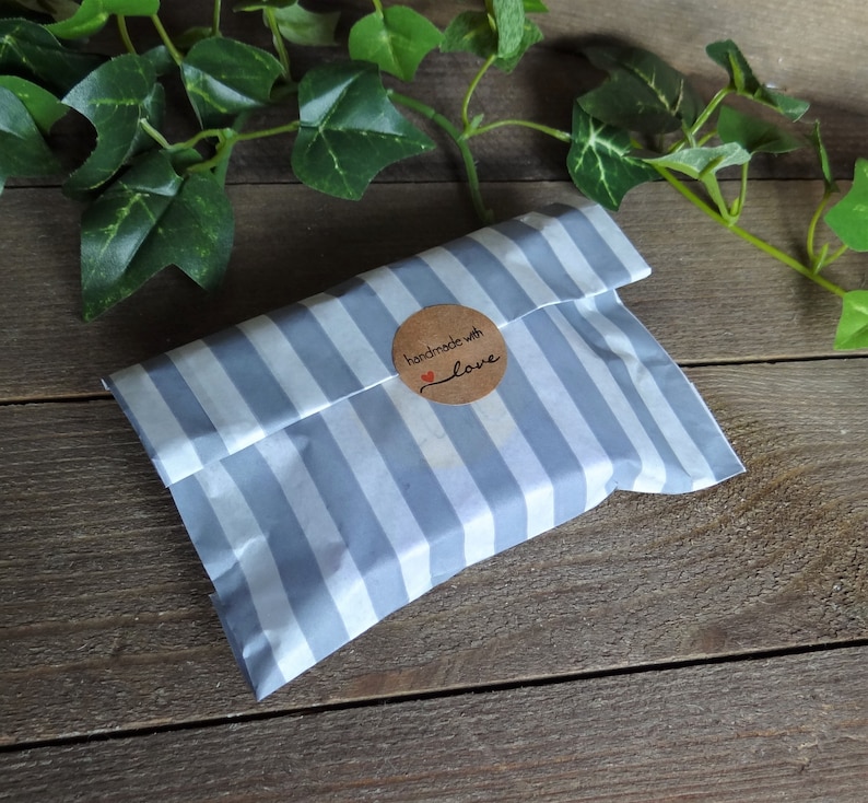 May include: A gray and white striped paper bag with a brown circle sticker that says "handmade with love".