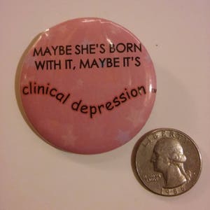 Puede incluir: Bot&oacute;n rosa con el texto "Maybe she's born with it, maybe it's clinical depression" en letras negras.