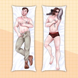 May include: Two body pillow cases featuring illustrations of men. The pillow case on the left features a man wearing khaki pants and brown boots. The pillow case on the right features a man wearing red underwear and a silver prosthetic arm.