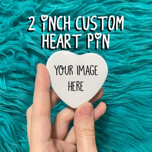 Op de afbeelding: Een witte hartvormige pin met de tekst "YOUR IMAGE HERE" erop. De pin is 5 cm in diameter.