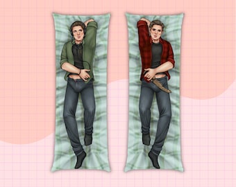 May include: Two body pillows with a green and white checkered pattern. Each pillow features a different illustration of a person wearing casual clothing. One person is wearing a green shirt and jeans, the other is wearing a red plaid shirt and jeans.
