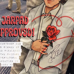 May include: A white t-shirt with a red heart and a rose printed on it. The shirt is signed by Jared Padalecki with the text "JARPAD APPROVED!" and "ONE CUSTOMER HAD HERS SIGNED BY JARED PADALECKI AT THE CHICAGO SUPERNATURAL CONVENTION IN 2024 <3".