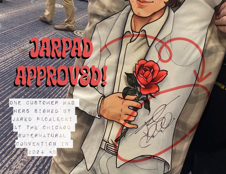 May include: A white t-shirt with a red heart and a rose printed on it. The shirt is signed by Jared Padalecki with the text "JARPAD APPROVED!" and "ONE CUSTOMER HAD HERS SIGNED BY JARED PADALECKI AT THE CHICAGO SUPERNATURAL CONVENTION IN 2024 <3".