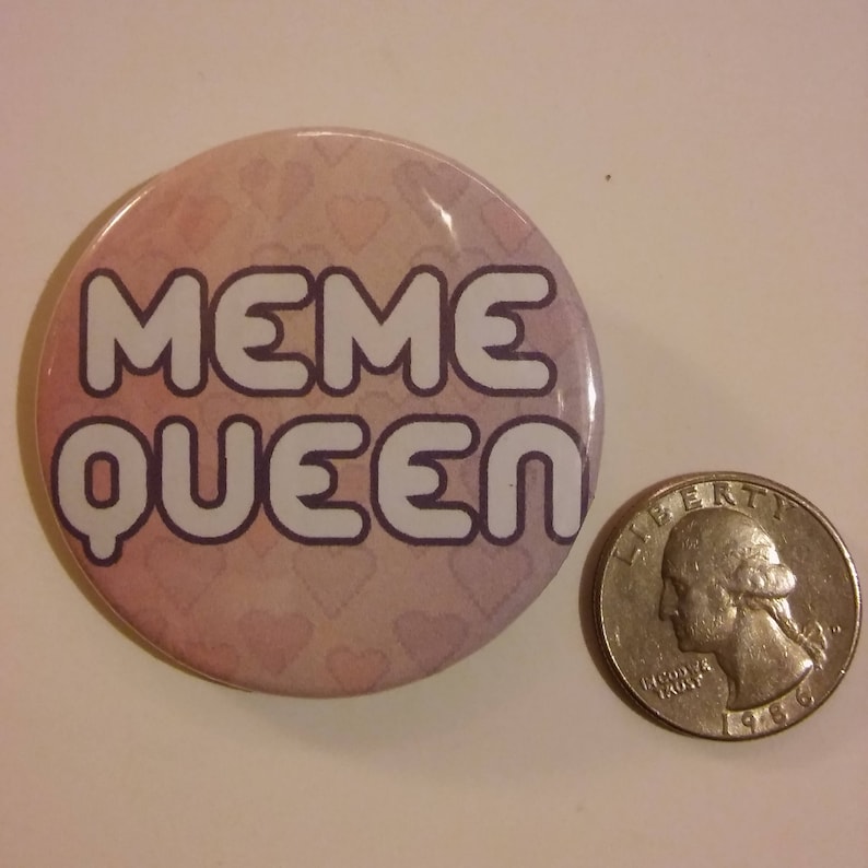 Puede incluir: Un bot&oacute;n rosa con un patr&oacute;n de corazones blancos y el texto "MEME QUEEN" en letras blancas.
