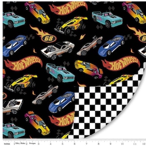 May include: Black fabric featuring a pattern of colorful Hot Wheels cars, flames, and the Hot Wheels logo. The cars are in various colors, including blue, yellow, and orange. A checkered pattern is visible on the right side. The fabric is measured in inches.
