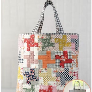 May include: A patchwork tote bag with a black and white gingham handle. The bag features a colorful quilt design with floral and geometric patterns. The text "Quilter's Big Tote" is at the top. The bag is reversible.