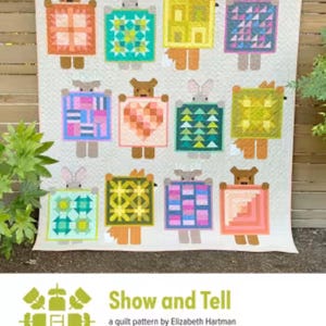 May include: A large quilt featuring multiple square panels, each depicting a whimsical animal figure holding a patterned square. The quilt showcases a variety of colors and geometric designs, with the text "Show and Tell" at the bottom.