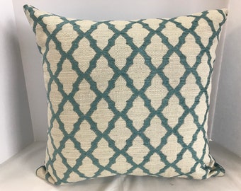 May include: A square throw pillow with a white background and a teal geometric pattern. The pattern is a repeating lattice design.
